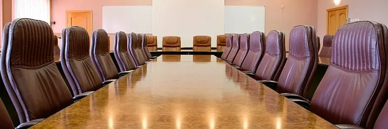 An empty conference room table with empty chairs placed around it.