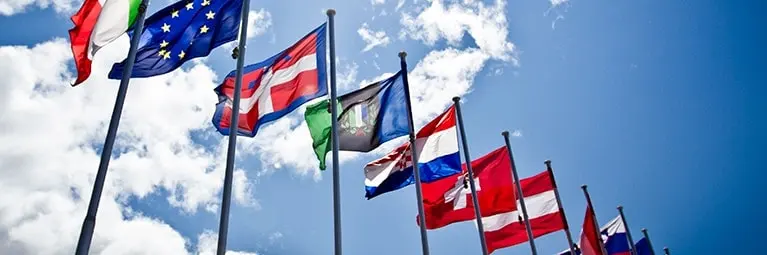A variety of country flags flying outside on a clear day.