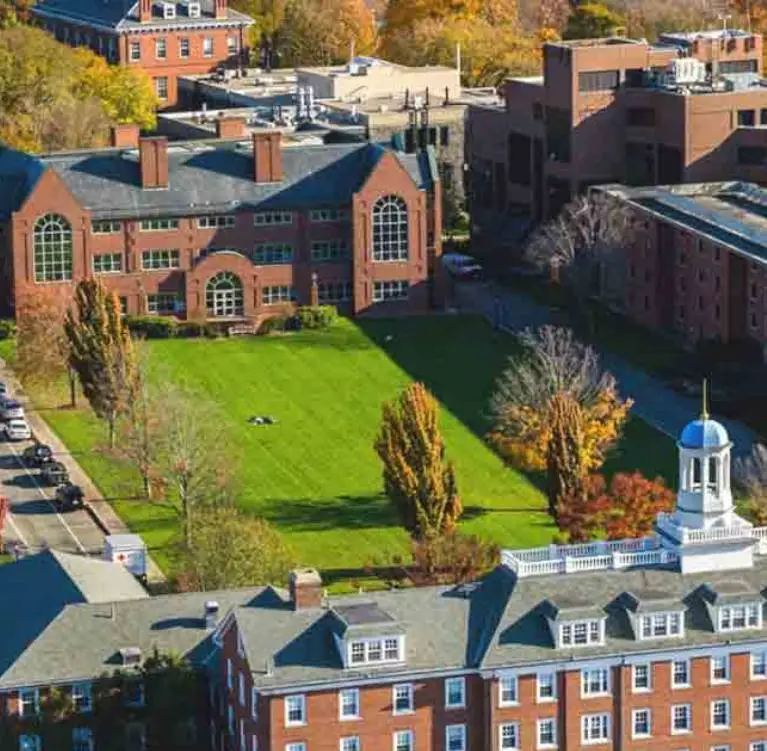 An aerial view of the Tufts University campus with brick buildings and a green field of grass
