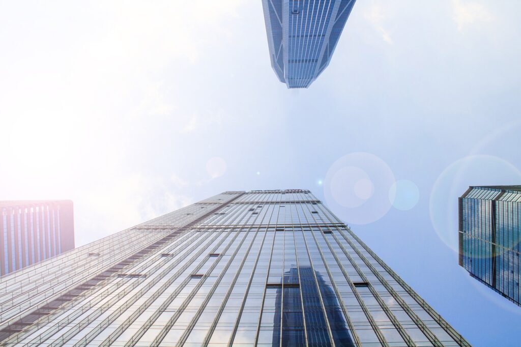 A view of the tops of skyscraper buildings as though the viewer is standing on the ground looking up.