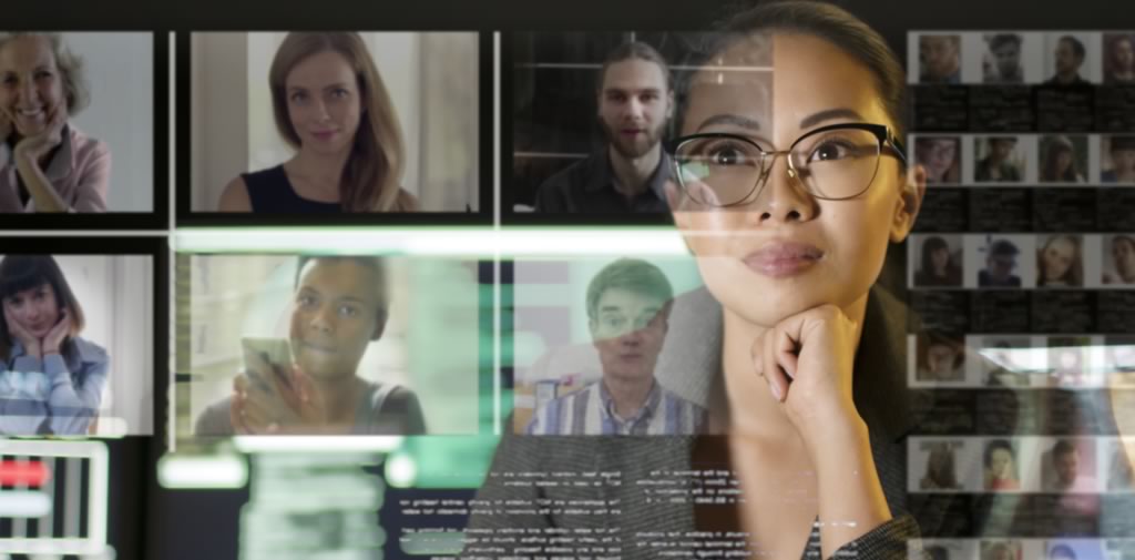 A working professional sits at a computer with a virtual meeting grid layered transparently on top.