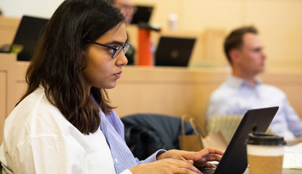 Student takes notes on her laptop during a lecture.